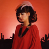 Female Model in Red Suede Top, Large Necklace and Featherd Hair